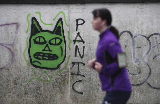 A woman runs past some graffiti in Edinburgh, the morning after stricter COVID-19 lockdown measures came into force for mainland Scotland, Tuesday January 5, 2021. (Photo by Andrew Milligan/PA Wire via AP Photo)