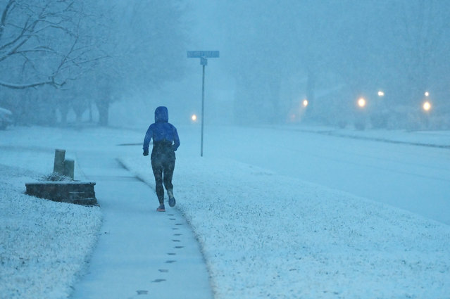 A pedestrian runs along Carrleigh Parkway as snow falls on Monday January 03, 2022 in Springfield, VA. (Photo by Matt McClain/The Washington Post)