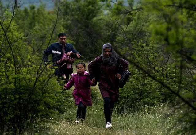 A Syrian family run in a forest in Macedonia after illegally crossing Greek-Macedonian border near the city of Gevgelija on April 23, 2016. Some 50,000 people, many of them fleeing the war in Syria, have been stranded in Greece since the closure of the migrant route through the Balkans in February. (Photo by Joe Klamar/AFP Photo)