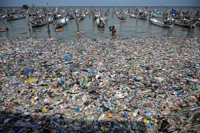A fisherman returns to the shore amid trash on the beach in Bangkalan, Madura Island, East Java province on May 13, 2024. (Photo by Juni Kriswanto/AFP Photo)