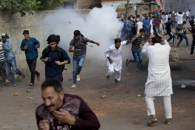 Kashmiris run for cover as a tear gas shell explodes near them during a protest in Srinagar Indian controlled Kashmir, Friday, August 23, 2019. Authorities intensified patrols Friday in Indian-controlled Kashmir's main city after posters appeared calling for a public march to a United Nations office to protest New Delhi's tightened grip on the disputed region. (Photo by Dar Yasin/AP Photo)