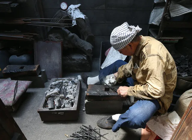 Myouchin Takumi, 65, as he finishes Hibashi iron bells made of iron on a production line at Myochin Honpo shop on April 25, 2014 in Himeji, Japan. (Photo by Buddhika Weerasinghe/Getty Images)