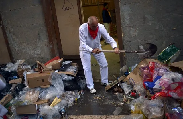 A man clears rubbish from his doorway on the seventh day of the San Fermin festival in Pamplona, northern Spain, July 12, 2015. (Photo by Vincent West/Reuters)
