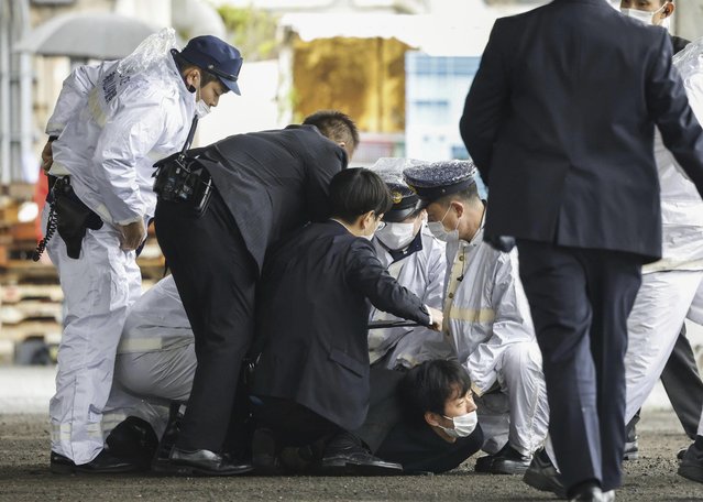 A man believed to be a suspect, center on the ground, is caught by police after he allegedly threw “the suspicious object”, as Japanese Prime Minister Fumio Kishida visited Saikazaki port for an election campaign event in Wakayama, western Japan Saturday, April 15, 2023. Kishida was evacuated unharmed Saturday after someone threw an explosive device in his direction while he was campaigning at the fishing port in western Japan, officials said. (Photo by Kyodo News via AP Photo)