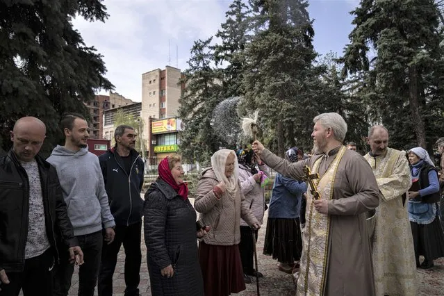 An Orthodox priest blesses believers during the Easter celebration in Slovyansk, eastern Ukraine, Saturday, April 23, 2022. (Photo by Evgeniy Maloletka/AP Photo)