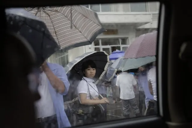 A lady waits in the rain, outside a restaurant, Saturday, July 25, 2015, in Pyongyang, North Korea. The rainy season in North Korea usually lasts through the month of July. (Photo by Wong Maye-E/AP Photo)