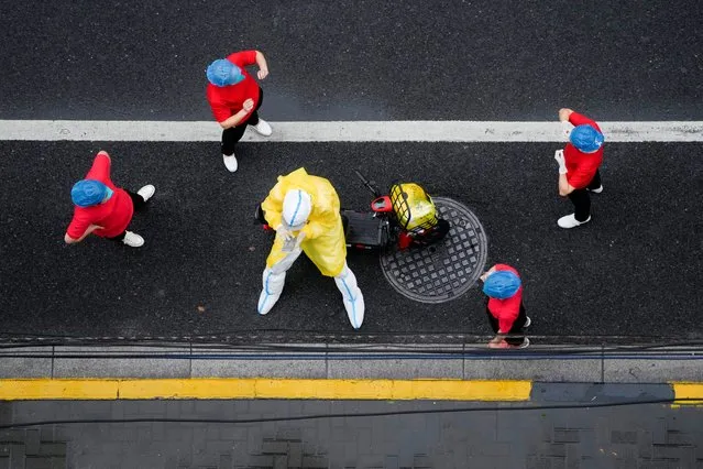 Workers in protective suits take a break on a street after nucleic acid testing during lockdown, amid the coronavirus disease (COVID-19) pandemic, in Shanghai, China, April 26, 2022. (Photo by Aly Song/Reuters)