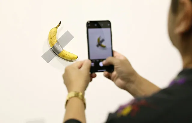 People post in front of Maurizio Cattelan's “Comedian” presented by Perrotin Gallery and on view at Art Basel Miami 2019 at Miami Beach Convention Center on December 6, 2019 in Miami Beach, Florida. Two of the three editions of the piece, which feature a banana duct-taped to a wall, have reportedly sold for $120,000. (Photo by Cindy Ord/Getty Images)