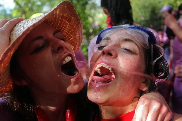 Revelers drink wine as they take part in the “Battle of Wine” (La batalla del vino de Haro), a wine fight, during the Haro Wine Festival, in Haro, in the northern province of La Rioja on June 29, 2014. More than nine thousand locals and tourists threw around 130.000 litres of wine at each other during the Haro Wine Festival, according to local media. (Photo by Cesar Manso/AFP Photo)