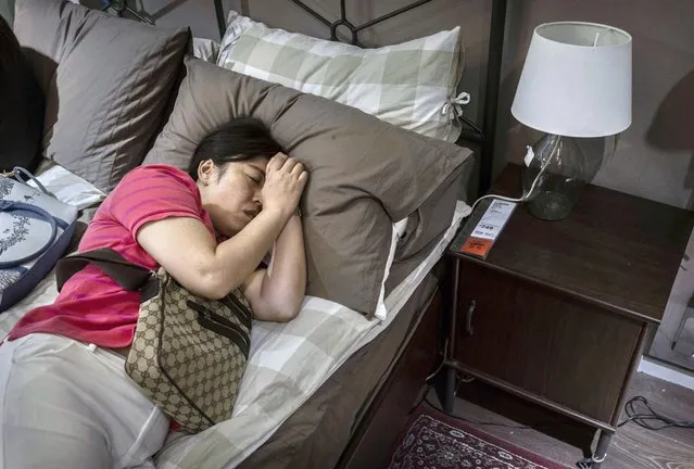 A Chinese shopper sleeps on a bed in the showroom of the IKEA store on July 6, 2014 in Beijing, China. Of the world's ten biggest Ikea stores, 8 of them are in China to cater to the country's growing middle class. The stores are designed with extra room displays given the tendency for customers to make a visit an all-day affair. Store management does not discourage shoppers from sleeping on Ikea furniture, even marking them with signs inviting customers to try them out. (Photo by Kevin Frayer/Getty Images)
