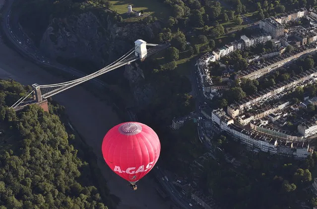 A balloon flies over Clifton Suspension Bridge in Bristol during a mass launch at the Bristol International Balloon Fiesta in south west England August 7, 2015. (Photo by Toby Melville/Reuters)