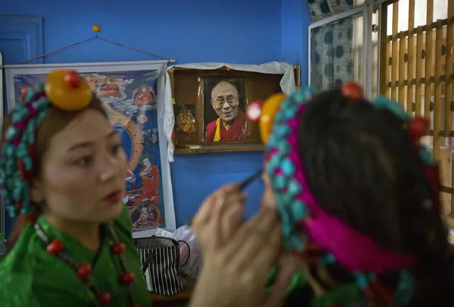 An exiled Tibetan woman applies make up to another as they prepare for a dance performance during celebrations marking the 82nd birthday of their spiritual leader the Dalai Lama at a Tibetan settlement in New Delhi, India, Thursday, July 6, 2017. Thousands belonging to Tibetan community waved white scarves and banners, lit incense and prayed for the Dalai Lama's long life as he turned 82 on Thursday. The Dalai Lama is currently visiting the Jokhang Gonpa, a Buddhist monastery, built in Ladakh in the Indian portion of Kashmir. (Photo by Manish Swarup/AP Photo)