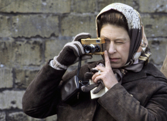 Queen Elizabeth ll takes photographs with her gold Rollei camera during a visit to the Badminton Horse Trials on April 26, 1974 in Badminton, England. (Photo by Anwar Hussein/Getty Images)