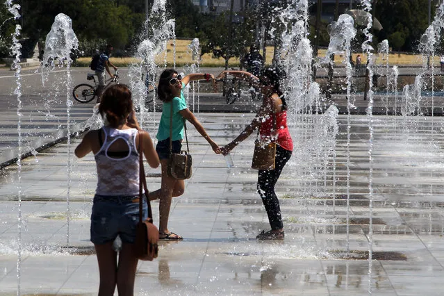 Tourists take photographs of themselves in the middle of water jets in a public fountain at the sea-front, in the northern Greek port of Thessaloniki, Monday, July 7, 2014. Temperatures are predicted to reach 36 degrees Celsius (96.8 Fahrenheit) in Greece. (Photo by Nikolas Giakoumidis/AP Photo)