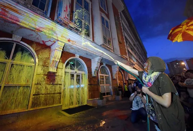 A protester drops a barrel of paint onto the facade front of the Ministry of Justice Building, during an anti-government protest  dubbed the “Colorful Revolution”, in Skopje, The Former Yogoslav Republic of Macedonia, 20 June 2016. (Photo by Nake Batev/EPA)