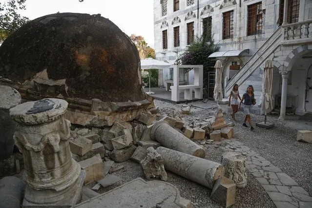 Tourists walk next to a fallen part of a minaret following an earthquake on the island of Kos, Greece, 21 July 2017. Two earthquake-related fatalities were reported on the island of Kos in the early morning hours of 21 July 2017, while several others were injured from a 6.7 magnitude earthquake that shook the island and much of the southeast Aegean region and southwestern Turkey. A 39-year-old Turk and a 27-year-old Swede are reportedly dead, according to sources. Five persons who have been seriously injured were transferred to the Heraklion University Hospital in Crete. Some buildings have suffered serious damage. The island's port has sustained damage while the airport is operating normally. (Photo by Yannis Kolesidis/EPA/EFE)