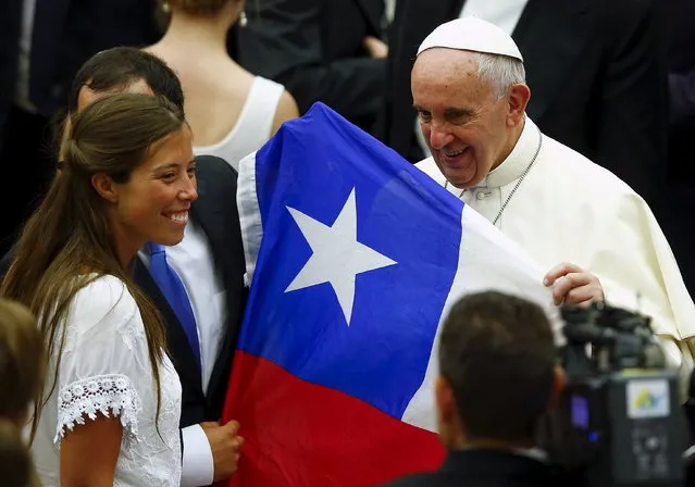 Pope Francis holds a Chilean flag which he received from a newly married couple during his Wednesday general audience in Paul VI hall at the Vatican August 12, 2015. (Photo by Remo Casilli/Reuters)