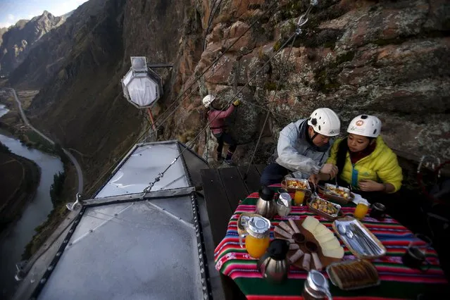 Guests have breakfast as another guest climbs to gather at the Skylodge Adventure Suites in the Sacred Valley in Cuzco, Peru, August 14, 2015. Tourists taking on an arduous climb up the steep cliff face of Peru's Sacred Valley are being rewarded for their efforts by being able to spend the night in transparent mountaintop sleeping pods at the “Skylodge Adventure Suites”. (Photo by Pilar Olivares/Reuters)