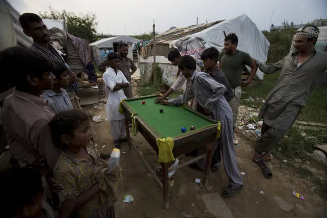 People from a nomad tribe play snooker in their neighborhood in Rawalpindi, Pakistan, Wednesday, August 19, 2015. These nomadic families earn their living collecting recyclable scrap to sell. (Photo by B. K. Bangash/AP Photo)