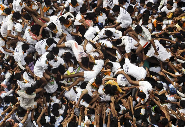 Indian youth collapse as they try to form a human pyramid to break the “Dahi handi”, an earthen pot filled with curd hanging above them, as part of celebrations to mark the Janmashtami festival in Mumbai, India, Tuesday, August15, 2017. The festival marks the birth of Hindu god Krishna and the act seeks to reenact the story of Lord Krishna stealing butter during his childhood. (Photo by Rajanish Kakade/AP Photo)