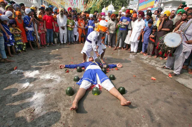A Sikh man with his eyes covered by a cloth breaks watermelons closely placed around performer as they practise Gatkha, a traditional form of martial art, during celebrations to mark the 413th anniversary of the installation of the Guru Granth Sahib, the religious book of Sikhs, in Amritsar, India August 22, 2017. (Photo by Munish Sharma/Reuters)