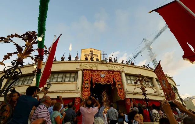 Hunters fire a fusillade of gunshots in a traditional salute as the statue of St Julian is carried out of the town parish church during the religious feast of St Julian, patron saint of hunters and of the town of St Julian's, outside Valletta, August 30, 2015. (Photo by Darrin Zammit Lupi/Reuters)