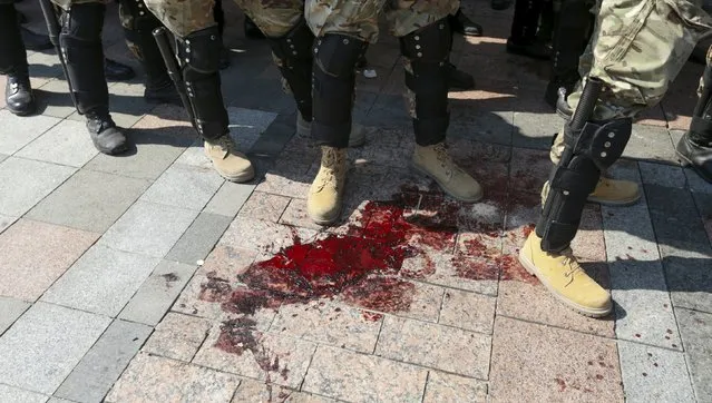 Interior ministry officers stand next to a pool of blood outside the parliament building in Kiev, Ukraine, August 31, 2015. At least four police and national guard were badly hurt when a grenade was lobbed from a crowd of nationalists demonstrating outside parliament against the “decentralisation” draft law that President Petro Poroshenko and his government are pushing as part of a blueprint to end separatist rebellion in the east. (Photo by Valentyn Ogirenko/Reuters)