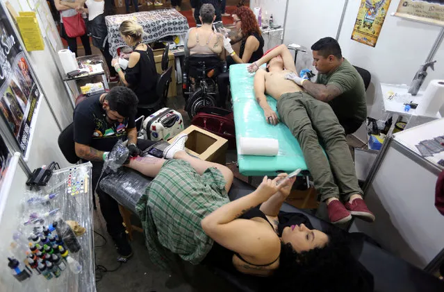Tattoo artists work on clients during the Tattoo Week SP 2016 in Sao Paulo, Brazil, July 23, 2016. (Photo by Paulo Whitaker/Reuters)
