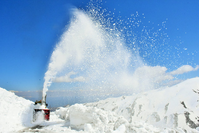 A view of a heavy machine cleaning out the snow-covered Cavustepe road in Turkey's eastern Mus province on April 15, 2020. Snow depth reaches approximately 10 meters in areas and roads around Kurtik Mount, as works to open roads to nearby villages are underway. (Photo by Yahya Sezgin/Anadolu Agency via Getty Images)