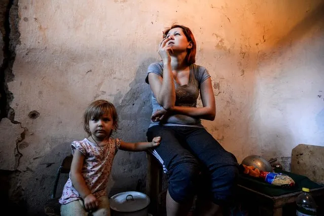 A mother and child hide in a bomb shelter in the Petrovskiy district of Donetsk, Ukraine, on September 1, 2014. The Petrovskiy district is currently a frontline and one of the districts which suffered the most from the artillery fights between the Ukrainian army and pro-Russian rebels. (Photo by Mstislav Chernov/Associated Press)