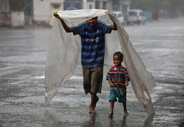 A homeless man and his son cover themselves with a plastic sheet to protect themselves from rain as they walk to a shelter, during a nationwide lockdown to slow the spreading of the coronavirus disease (COVID-19), in Kolkata, India, April 27, 2020. (Photo by Rupak De Chowdhuri/Reuters)