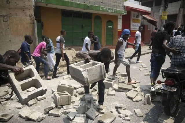 Protesters build a road barricade during a protest to demand that Haitian Prime Minister Ariel Henry step down and a call for a better quality of life, in Port-au-Prince, Haiti, Wednesday, September 7, 2022. (Photo by Odelyn Joseph/AP Photo)