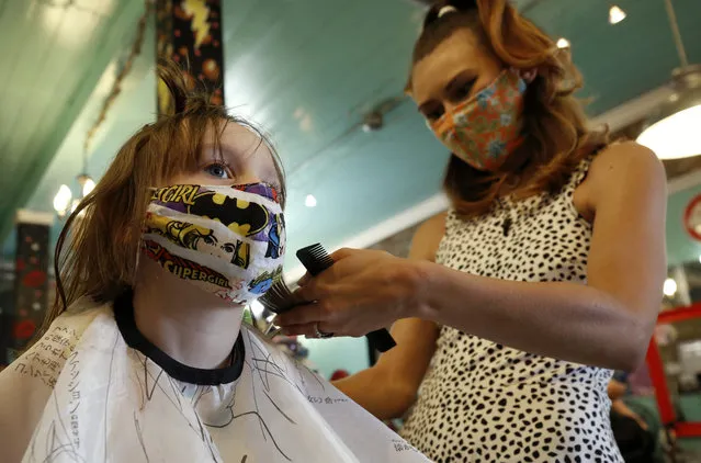 In this May 4, 2020, file photo, Robin Sotomayor, 5, wears a Supergirl face mask as she gets her hair done by Haylee Cummins at Rockabetty's Hair Parlor, in Yuba City, Calif. Donning a mask will be as common as putting on a cap or sunglasses for Californians as the state begins gradually easing stay-at-home orders, but rules about face coverings vary from county to county and it is unclear what enforcement might look like. (Photo by Rich Pedroncelli/AP Photo/File)