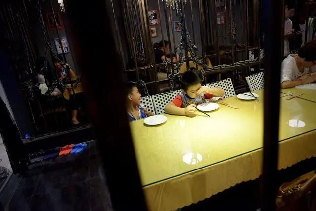 This picture taken on September 9, 2014 shows a family preparing to have dinner at a prison themed restaurant in Tianjin. (Photo by Wang Zhao/AFP Photo)