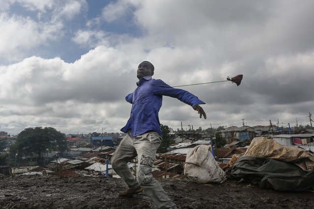 A supporter of the opposition coalition the National Super Alliance (NASA) and its presidential candidate Raila Odinga, uses a slingshot to throw stones at police officers during their protest in Kibera slum, one of the opposition strongholds in Nairobi, Kenya, 26 October 2017. (Photo by Dai Kurokawa/EPA/EFE)