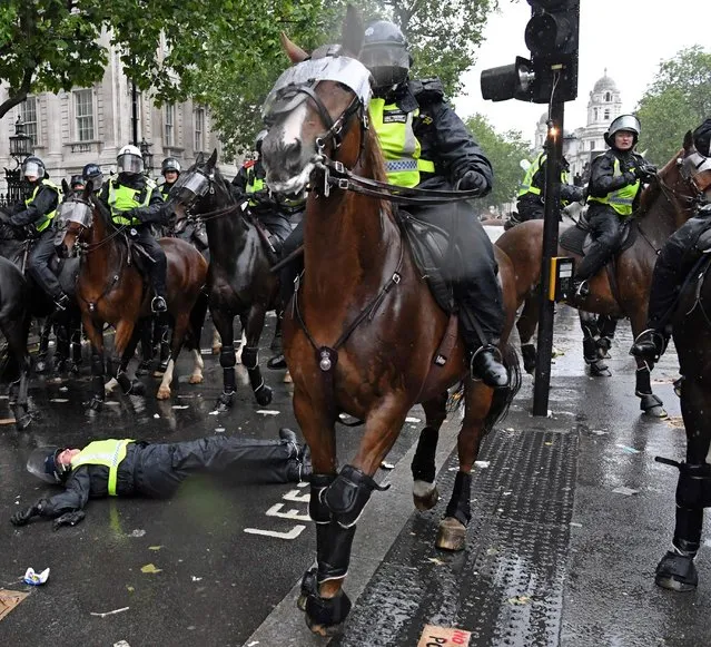 The bulb from a broken traffic light shines as a mounted police officer lays on the road after being unseated from their horse on Whitehall, near the entrance to Downing Street in central London on June 6, 2020, during a demonstration organised to show solidarity with the Black Lives Matter movement in the wake of the killing of George Floyd, an unarmed black man who died after a police officer knelt on his neck in Minneapolis. (Photo by Daniel Leal-Olivas/AFP Photo)