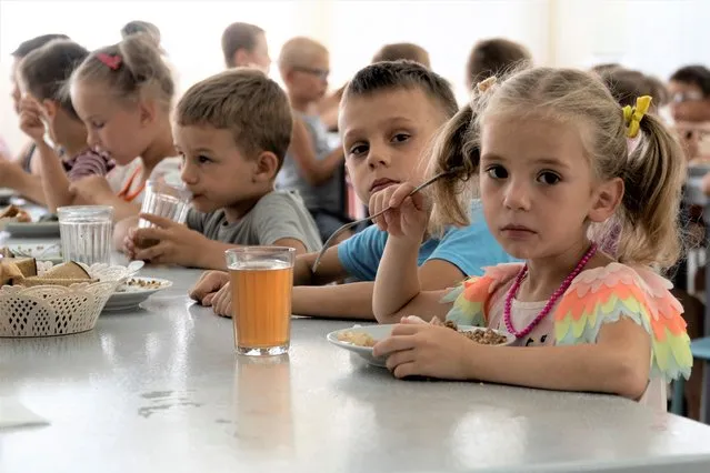Children from an orphanage in the Donetsk region, eat a meal at a camp in Zolotaya Kosa, the settlement on the Sea of Azov, Rostov region, southwestern Russia, Friday, July 8, 2022. Russia's open effort to adopt Ukrainian children and bring them up as Russian is emerging as one of the most explosive issues of the war. (Photo by AP Photo/Stringer)