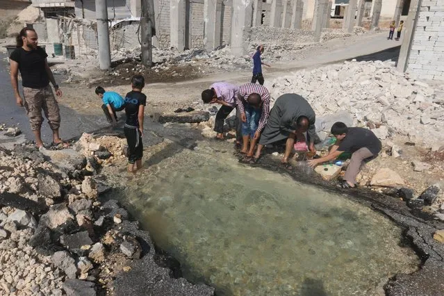 Residents cool down with water from a damaged water pipe due to shelling in the rebel held neighbourhood of Sheikh Saeed, in Aleppo, Syria  August 20, 2016. (Photo by Abdalrhman Ismail/Reuters)