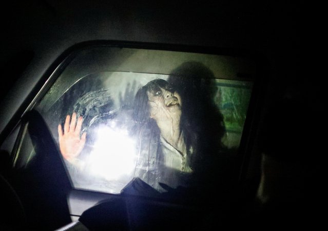 An actor dressed as a zombie performs during a drive-in haunted house show by Kowagarasetai (Scare Squad), for people inside a car in order to maintain social distancing amid the spread of the coronavirus disease (COVID-19), at a garage in Tokyo, Japan on July 3, 2020. (Photo by Issei Kato/Reuters)