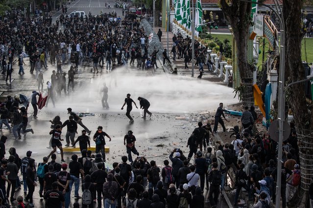 Activists clash with Indonesian Police officers as water cannons are used during a protest against the military law revision on March 24, 2025 in Surabaya, Indonesia. On March 20, Indonesia's House of Representatives passed a revision to military law, allowing military officers to serve in more government posts and take up civilian positions without resigning from the Indonesian National Armed Forces. This amendment has drawn criticism from civil society groups, who warn it could signal a return to the repressive New Order era under former President Soeharto, when military officers dominated civilian affairs.Critics argue that this change could lead to abuse of power, human rights violations, and political impunity for army personnel, reminiscent of the era under dictator Suharto, who stepped down in 1998. The timing is particularly significant as Indonesia is now led by President Prabowo Subianto, an ex-special forces general and former son-in-law of Suharto, who was inaugurated in October 2024. (Photo by Robertus Pudyanto/Getty Images)