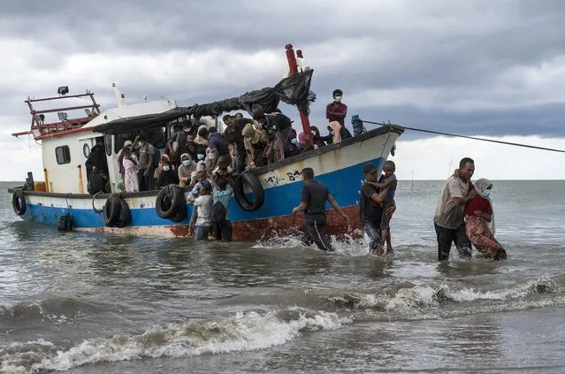 Local fisherman help ethnic-Rohingya people as they arrive on Lancok Beach, North Aceh, Indonesia, Thursday, June 25, 2020. Indonesian fishermen discovered dozens of the hungry, weak Rohingya Muslims on the wooden boat adrift off Indonesia's northernmost province of Aceh late Monday, an official said. (Photo by Zik Maulana/AP Photo)