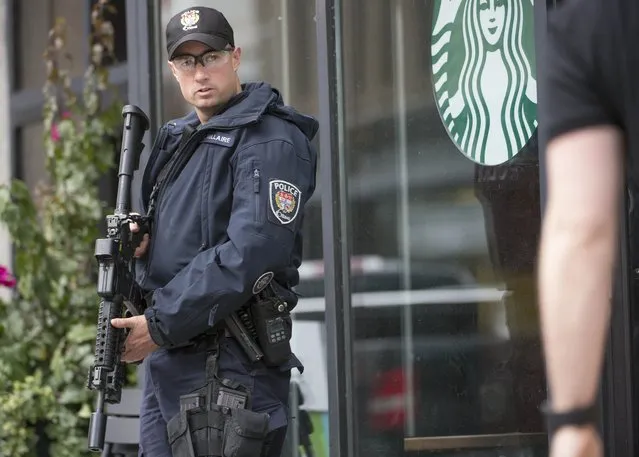 An police officer stands watch outside a Starbucks in Ottawa,Ontario after multiple shootings on October 22, 2014. Gunfire echoed through the Gothic halls of the Canadian parliament Wednesday as police shot dead a gunman suspected of killing a soldier guarding a nearby war memorial before storming the building. Police said an investigation was continuing, but did not confirm earlier reports that more gunmen were involved. Heavily armed officers backed by armored vehicles sealed off the building. (Photo by Peter McCabe/AFP Photo)