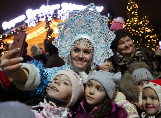 A woman dressed as a snow maiden takes a selfie with children during a festive parade in Ryazan, Russia on December 23, 2017. (Photo by Alexander Ryumin/TASS/Barcroft Images)
