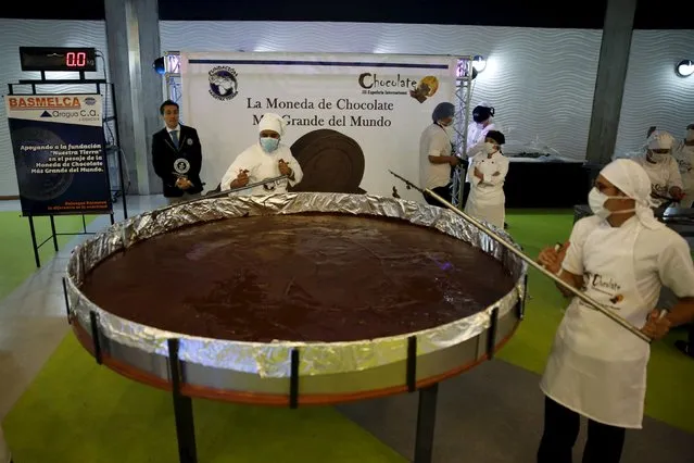 Carlos Martinez (L), a representative of the Guinness World Records, examines the cooking process of a chocolate coin during an attempt to break the Guinness World Record for the biggest chocolate coin in Caracas, Venezuela, October 1, 2015. (Photo by Carlos Garcia Rawlins/Reuters)