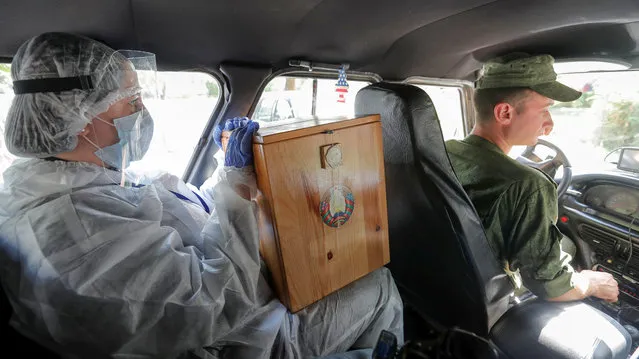 A member of an electoral commission holding a mobile ballot box and wearing protective gear sits inside a car while visiting local residents during the presidential election in Minsk, Belarus on August 9, 2020. (Photo by Vasily Fedosenko/Reuters)