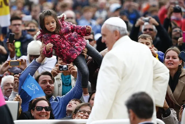 A man holds up a child as Pope Francis arrives to lead the Wednesday general audience in Saint Peter's square at the Vatican October 29, 2014. (Photo by Tony Gentile/Reuters)