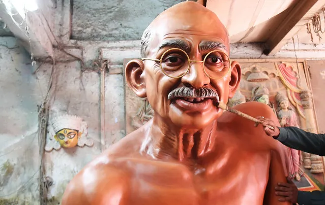 An Indian artisan removes the dust from the statue of Mahatma Gandhi inside a workshop in Kolkata on January 8, 2018. Statues of different Indian classical musicians along with a statue of the father of nation Mahatma Gandhi will be displayed on the Tableau of All India Radio (AIR), the national public radio broadcaster of India, during the Delhi Republic Day parade. The parade takes place every year on January 26 at Rajpath in New Delhi and it is the largest and most important parade that marks the Republic Day celebrations in India. (Photo by Dibyangshu Sarkar/AFP Photo)