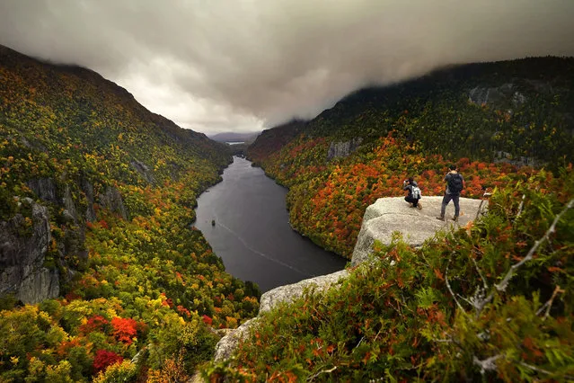 Two visitors photograph the colorful autumn view at the Indian Head vista overlooking Lower Ausable Lake in the Adirondacks, Sunday, September 27, 2020, near Keene Valley, N.Y. (Photo by Robert F. Bukaty/AP Photo)