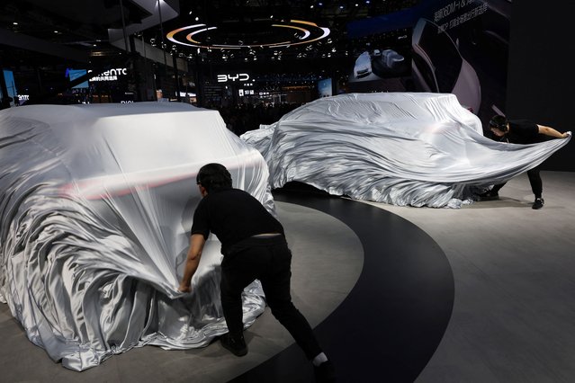 Staff members unveil vehicles at the BYD booth during a media day for the Auto Shanghai show in Shanghai, China on April 23, 2025. (Photo by Go Nakamura/Reuters)