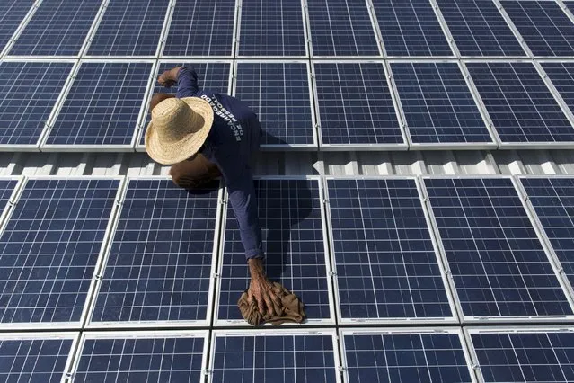 Francisco da Silva Vale, 61, cleans solar panels which power ice machines at Vila Nova do Amana community in the Sustainable Development Reserve, in Amazonas state, Brazil, September 22, 2015. (Photo by Bruno Kelly/Reuters)